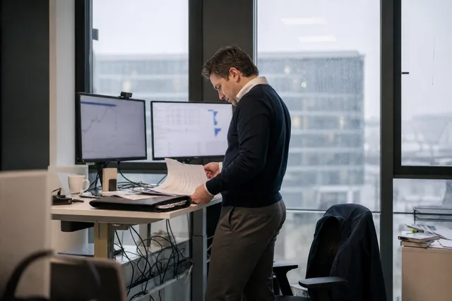 Fintech professional reviewing charts at a standing desk